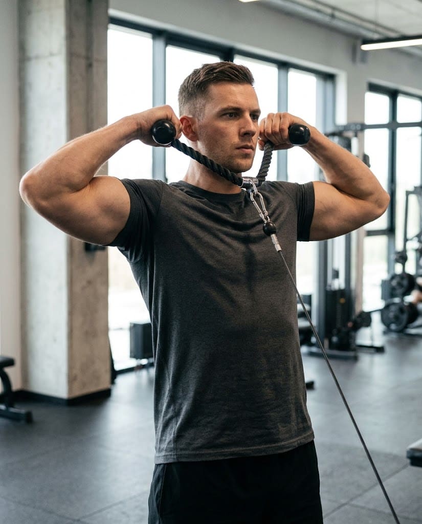 Końcowa pozycja face pull z dłońmi obok uszu